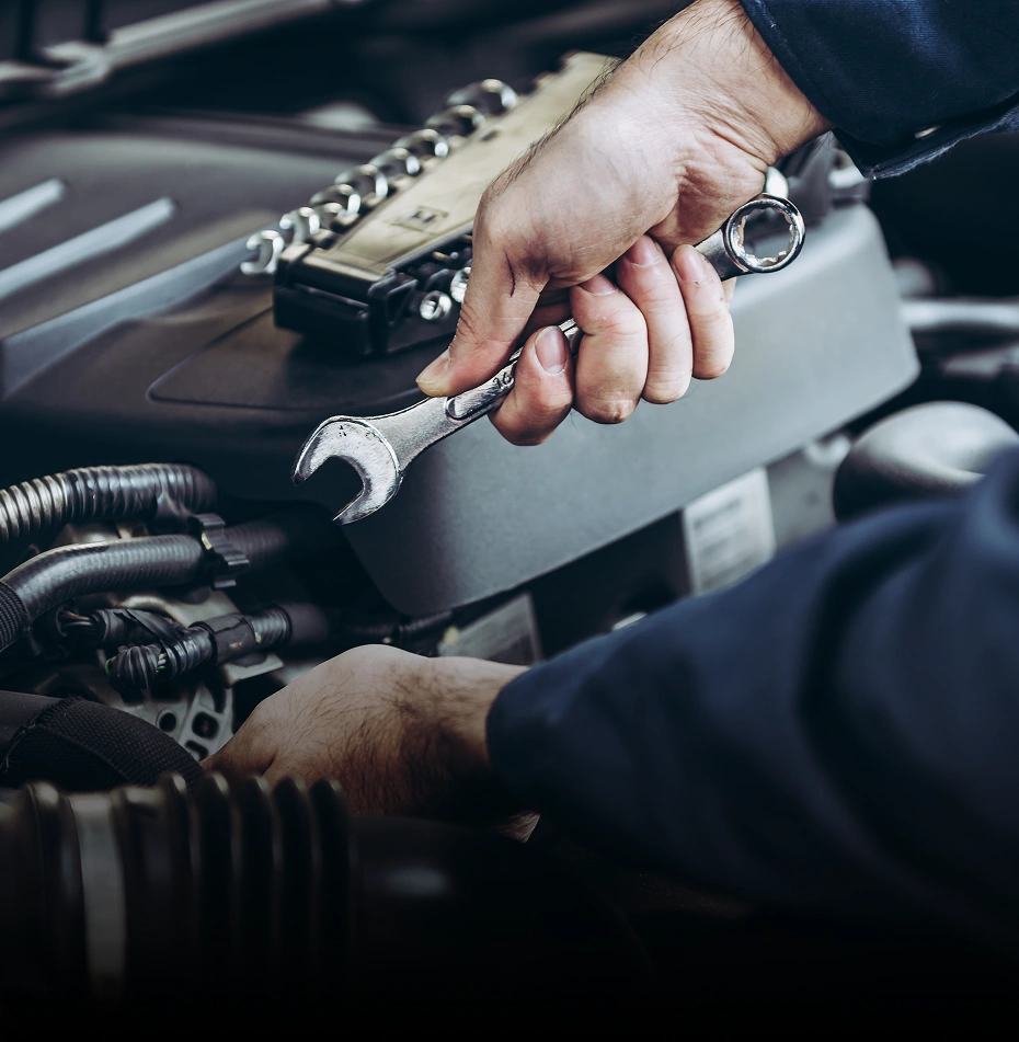 Automotive worker repairing car engine in workshop, emphasizing vehicle maintenance and service.