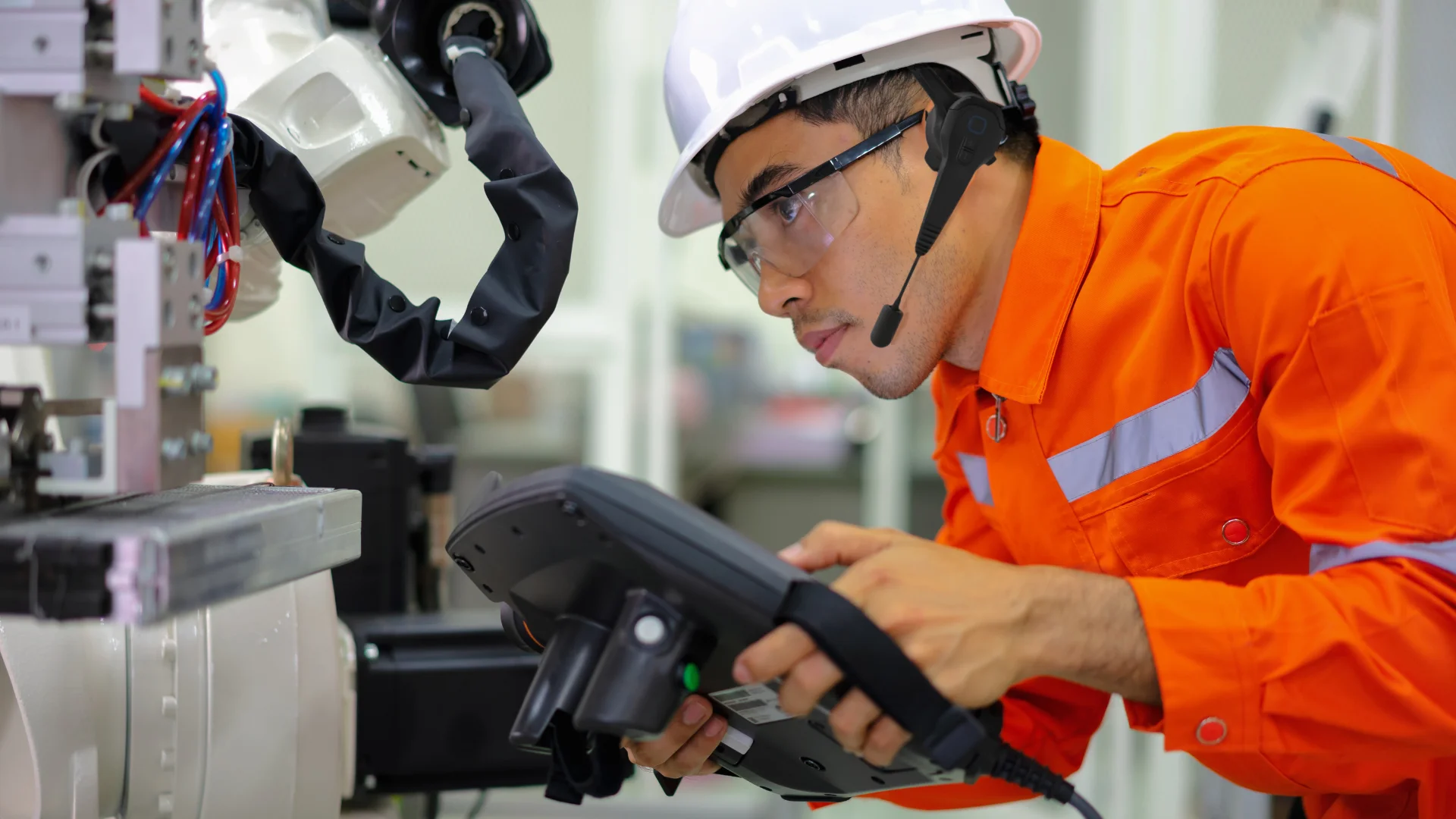 An operator equipped with a headset is inspecting a machinery.